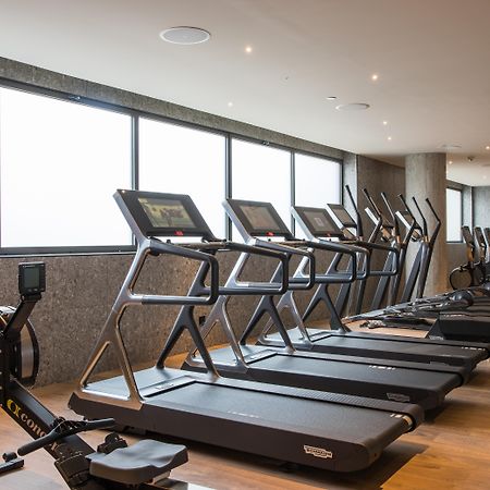 Grand Hyatt Barcelona Ξενοδοχείο Εξωτερικό φωτογραφία The photo shows a modern gym space featuring several pieces of exercise equipment. In the foreground, there are treadmills, while in the background, there are elliptical machines lined up against large windows that provide natural light. The flooring