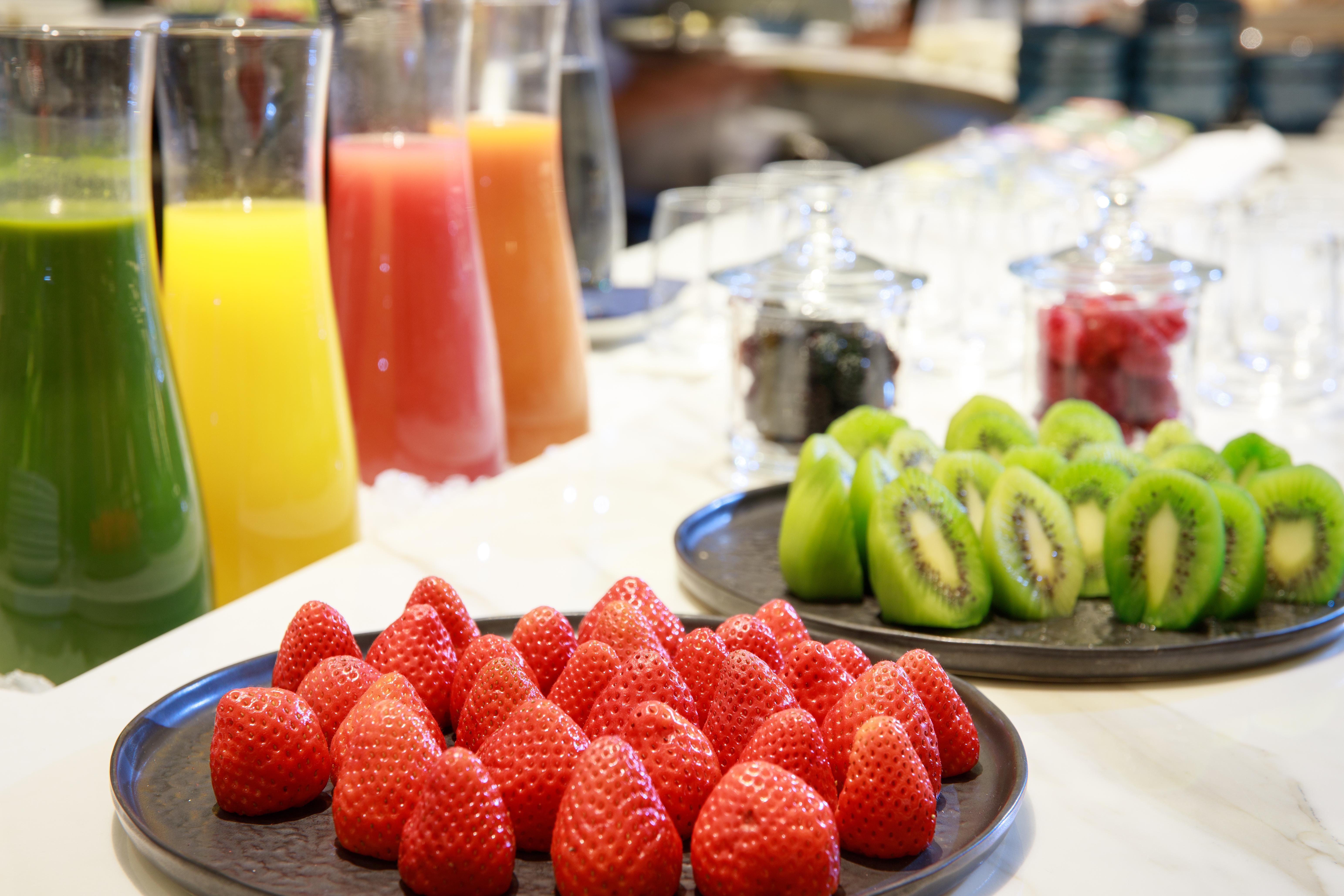 Grand Hyatt Barcelona Ξενοδοχείο Εξωτερικό φωτογραφία The photo displays a vibrant assortment of fresh fruits and juices. In the foreground, there is a plate of bright red strawberries neatly arranged. Behind the strawberries, there are several tall glasses filled with various juices, including orange, 