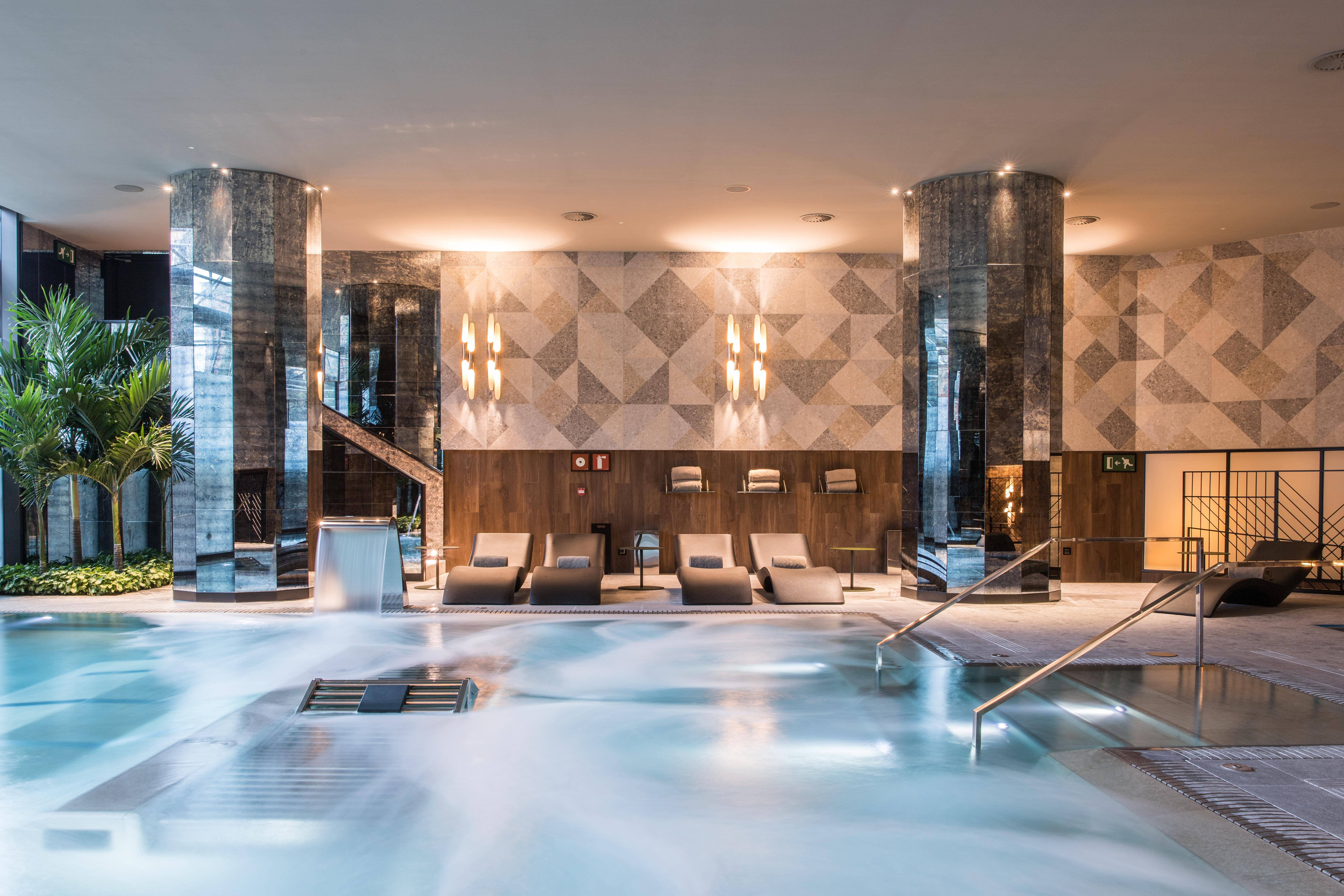 Grand Hyatt Barcelona Ξενοδοχείο Εξωτερικό φωτογραφία The photo shows a sophisticated spa area featuring a large, inviting pool with a calm, relaxing atmosphere. The pool area is surrounded by elegant columns and has a modern design. There are comfortable lounge chairs positioned nearby, and the lightin