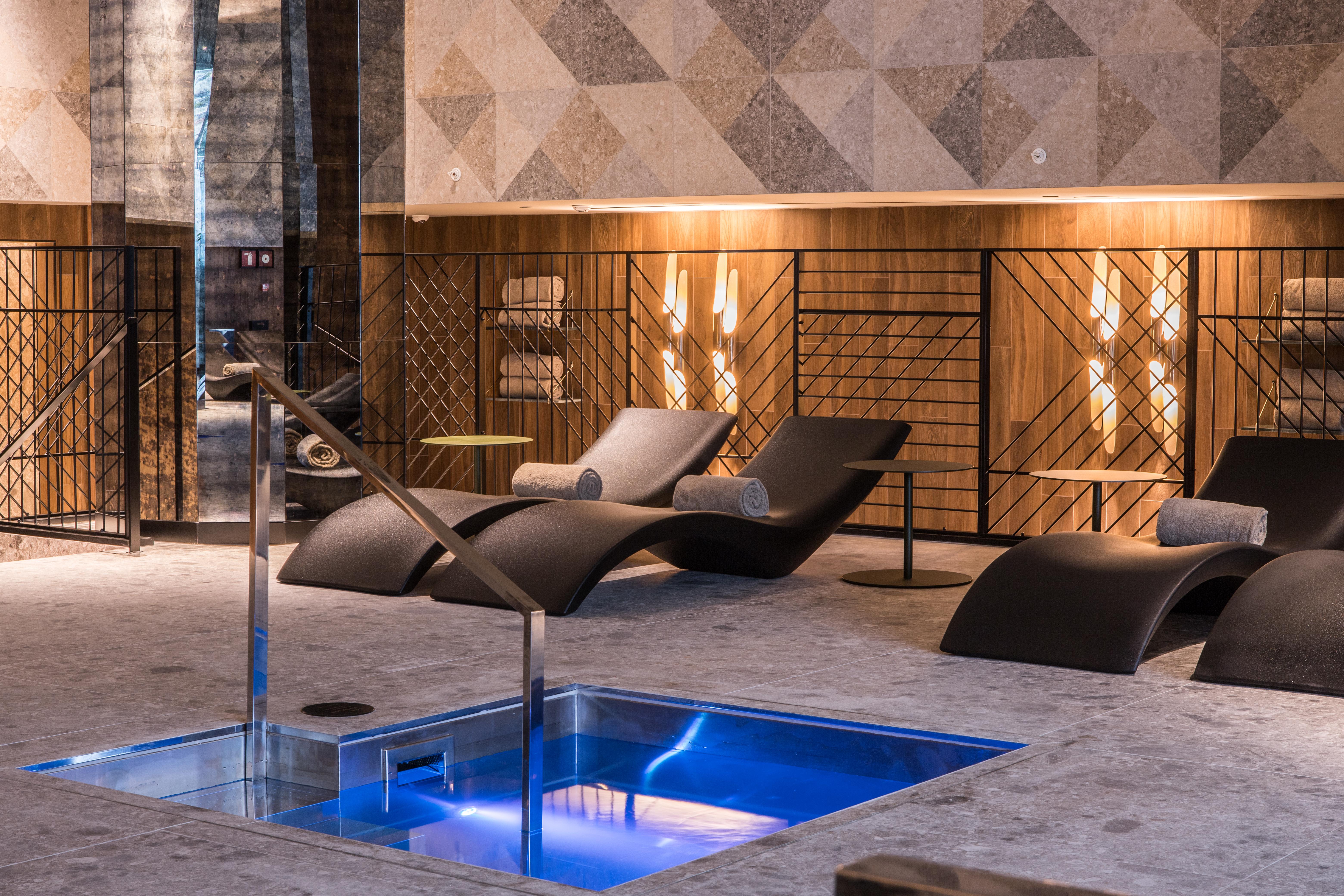 Grand Hyatt Barcelona Ξενοδοχείο Εξωτερικό φωτογραφία The photo shows a modern spa or relaxation area. In the foreground, there is a small rectangular pool of water with a sleek metal railing. Surrounding the pool are comfortable lounge chairs, designed for relaxation, likely positioned for users to unw